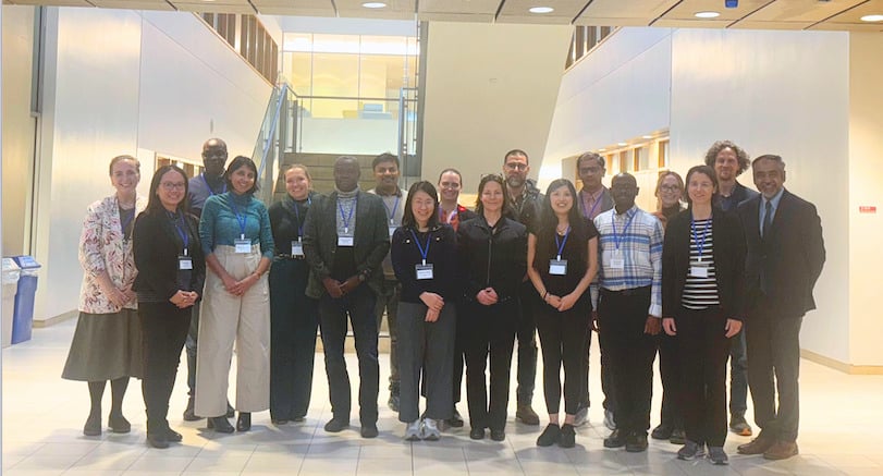 A group of workshop participants standing together and smiling for a photo at the Integrated One Health Research and Policy Workshop: Bridging Sectors and Disciplines. The group is arranged in a single row indoors. 